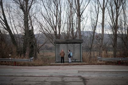 Dos personas esperan la llegada del autobús que estaba a punto de dejar de funcionar.