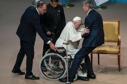Ayudan al papa Francisco a ponerse de pie cuando llega a una reunión con autoridades, la sociedad civil y diplomáticos en la Sala de Conciertos Qazaq en Nur-Sultan, Kazajstán, el 13 de septiembre de 2022