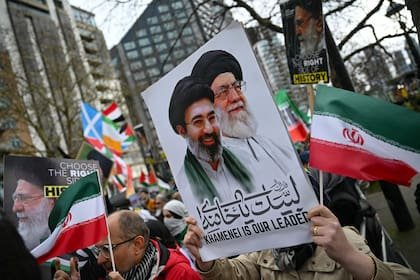 Un manifestante sostiene una pancarta con la imagen del difunto ayatolá Ali Khamenei (centro derecha) y del nuevo líder supremo de Irán, Mojtada Khamenei (centro izquierda), durante una protesta anual, este año estática, organizada por el grupo propalestino Al-Quds en el centro de Londres