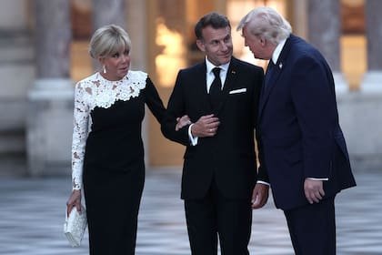 El presidente de Francia, Emmanuel Macron (centro), y su esposa, Brigitte Macron (izq.), reciben al presidente de Estados Unidos, Donald Trump (der.), en el Palacio de Versalles antes de una cena para conmemorar el 250.º aniversario de la independencia de Estados Unidos, el 17 de junio de 2026, en Versalles, al sudoeste de París.