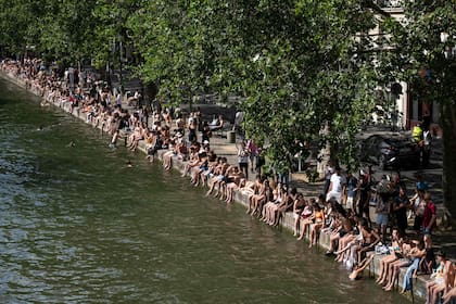 Personas toman sol junto al Canal Saint-Martin, habilitado para nadar por la ola de calor en París