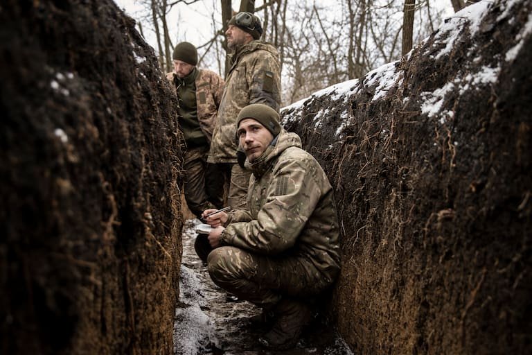 Soldiers with the Ukrainian armed forces take shelter in a trench as their fellow soldiers fire a Howitzer at Russian positions, in the Donbas Region of eastern Ukraine on Tuesday, Feb. 14, 2023. Ukraine’s Western allies must help its armed forces learn to use a wide variety of modern weapons systems, from artillery and tanks to armored vehicles and missiles, to accomplish a spring offensive against Russian forces that could swing the battlefield momentum toward Kyiv, U.S. Defense Secretary Lloyd Austin said on Tuesday. (Tyler Hicks/The New York Times)