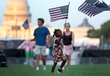 Una niña sostiene una bandera estadounidense durante la Gran Feria Estatal Estadounidense, organizada en Washington por los festejos del 250° aniversario