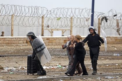 Miembros de las fuerzas de seguridad marroquíes escoltan a mujeres desde el lugar donde se produjeron enfrentamientos cerca de Fnideq, en la frontera entre Marruecos y España, el 31 de julio