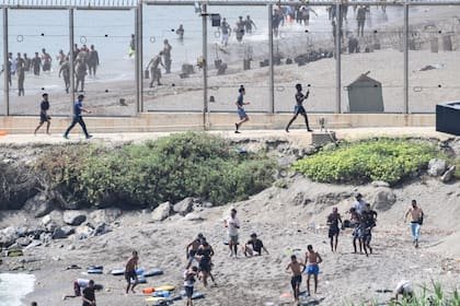 Un grupo de migrantes avanza por la costa tras cruzar desde el vecino Marruecos hacia Ceuta, el enclave español en el norte de África. Más de 1500 migrantes han llegado a Ceuta en la última semana, la mayoría a nado, según las autoridades españolas