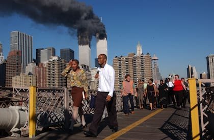 La gente camina sobre el puente de Brooklyn mientras el World Trade Center arde el 11 de septiembre de 2001 después de que dos aviones secuestrados se estrellaran contra las Torres Gemelas en la ciudad de Nueva York