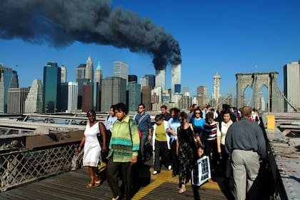 La gente cruza el Puente de Brooklyn alejándose de las torres de World Trade en llamas antes de su derrumbe