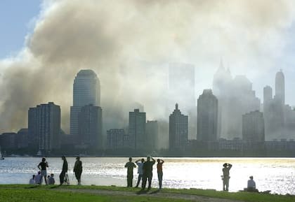 La gente observa desde Jersey City, Nueva Jersey, mientras el humo se eleva desde el bajo Manhattan