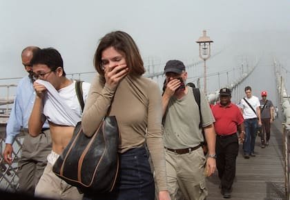 Las personas se cubren la cara mientras cruzan el Puente de Brooklyn entre el humo y el polvo en Manhattan