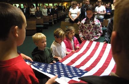 Los niños sostienen una bandera durante un servicio conmemorativo en la Iglesia Católica Romana St. Michael the Archangenl en Greenwich, el 14 de septiembre de 2001