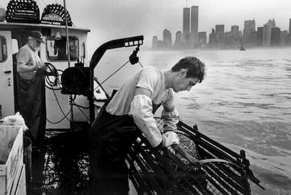 Trabajadores de un barco langostero revisan sus trampas en el puerto de Nueva York el 19 de julio de 1988, en el fondo la ciudad de Nueva York con las imponentes Torres Gemelas
