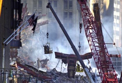 Un par de soldadores son sacados de los escombros con una grúa después de cortar una sección de metal en el sitio del desastre del World Trade Center, el sábado 15 de septiembre de 2001