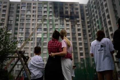 Vecinos observan mientras los bomberos trabajan después de que un ataque con drones rusos alcanzara un edificio residencial en Kiev