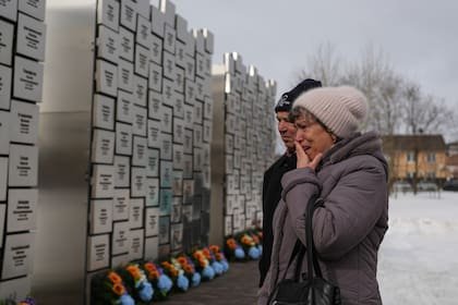Parientes de fallecidos durante la ocupación rusa lloran en el Muro de Recuerdo durante una ceremonia para conmemorar el cuarto aniversario de la invasión rusa (Archivo)