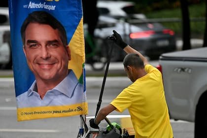 Un hombre camina junto a una pancarta con la imagen de Flavio Bolsonaro, en San Pablo, Brasil