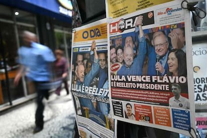 Un hombre pasa junto a un quiosco de periódicos cuyas portadas muestran la victoria de Lula da Silva
