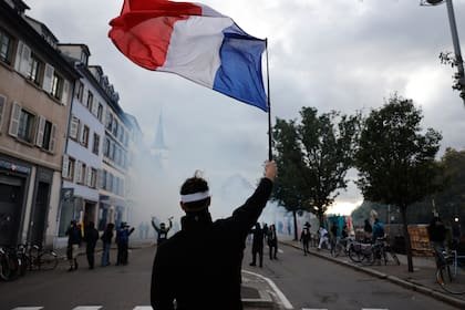 Un manifestante sostiene una bandera francesa durante una protesta contra el aumento del costo de vida en Estrasburgo, Francia, el sábado 24 de octubre 