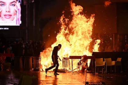 Una barricada de cartones y basura arde mientras los manifestantes se enfrentan a la policía durante una protesta antigubernamental en Italia, el 17 de octubre