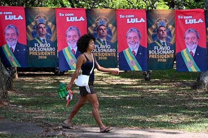 Una mujer pasa junto a banderas y toallas con las imágenes de los candidatos del balotaje, a la venta en una calle de Brasilia